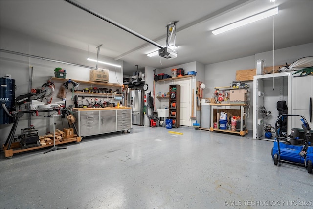 garage featuring a workshop area, a garage door opener, and stainless steel refrigerator with ice dispenser