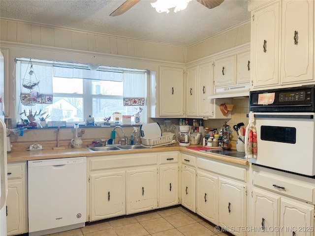 kitchen featuring under cabinet range hood, light tile patterned floors, white appliances, a ceiling fan, and a sink