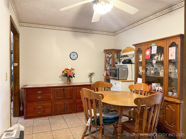 dining area featuring ceiling fan, light tile patterned floors, and a textured ceiling