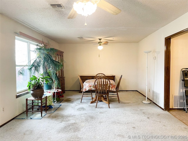 carpeted dining area featuring baseboards, a ceiling fan, visible vents, and a textured ceiling