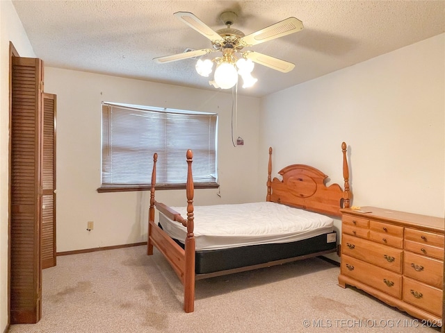 bedroom featuring a textured ceiling, a ceiling fan, baseboards, and light carpet