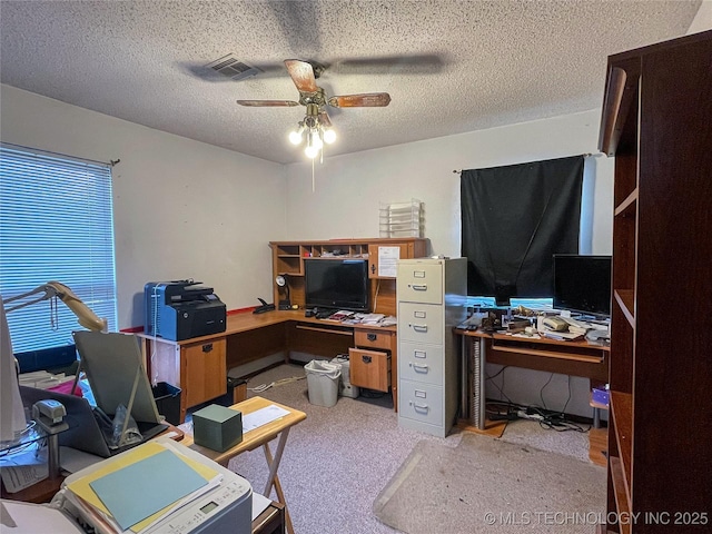 carpeted office featuring a ceiling fan, visible vents, and a textured ceiling