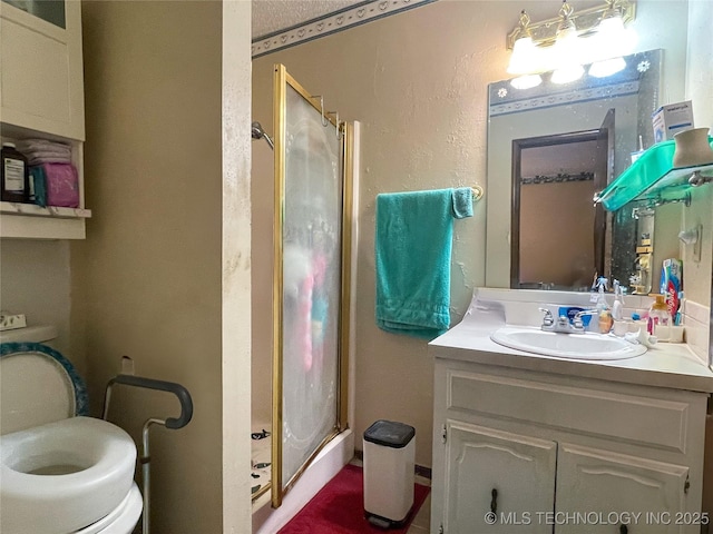 full bath with vanity, toilet, a textured wall, and a stall shower