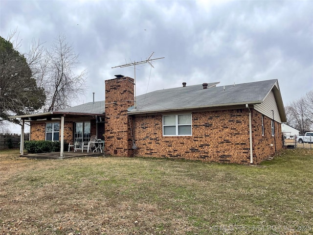 rear view of house with a patio, a chimney, crawl space, a lawn, and brick siding