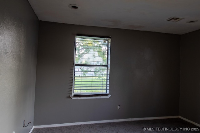 carpeted spare room featuring visible vents, a healthy amount of sunlight, and baseboards