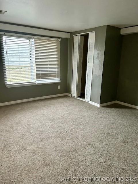 spare room featuring carpet flooring, visible vents, and baseboards