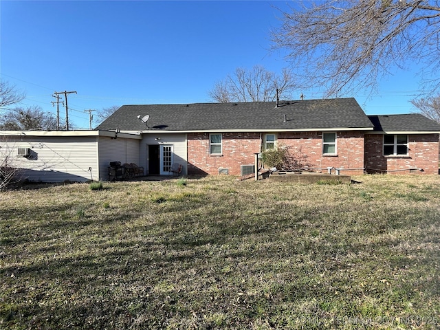 back of house with a lawn, brick siding, and roof with shingles