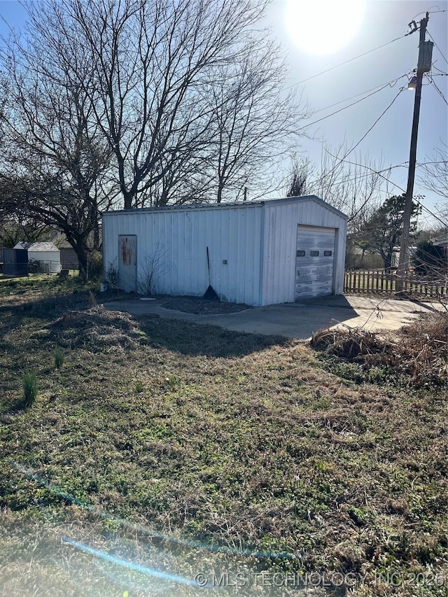 view of outdoor structure featuring an outbuilding, fence, and driveway