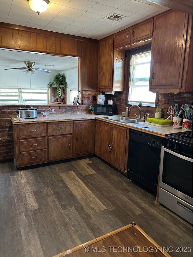 kitchen featuring visible vents, dark wood-style flooring, a sink, black appliances, and light countertops