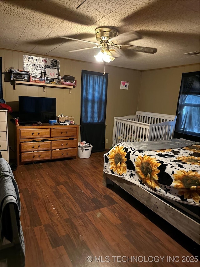 bedroom with a ceiling fan, wood finished floors, and visible vents