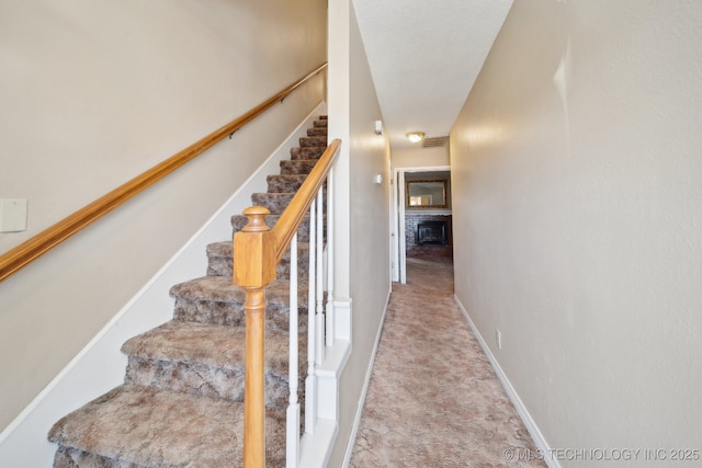 stairway with visible vents, baseboards, and a fireplace