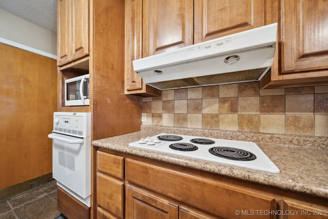 kitchen with white appliances, backsplash, under cabinet range hood, and a textured ceiling