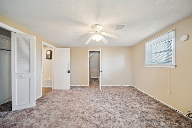 unfurnished bedroom featuring a ceiling fan, baseboards, visible vents, a textured ceiling, and carpet flooring