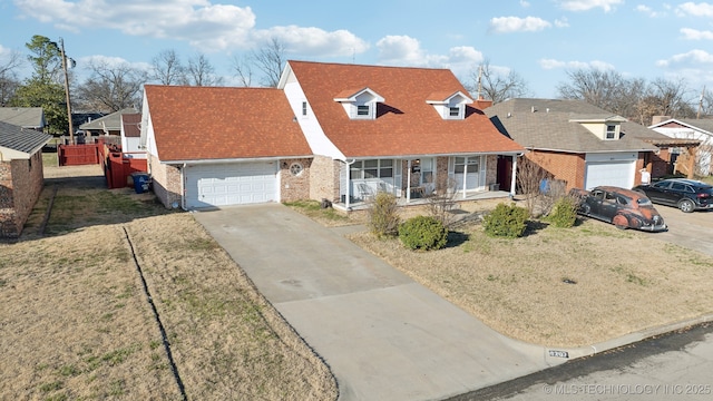 cape cod home featuring a porch, concrete driveway, a shingled roof, a garage, and brick siding