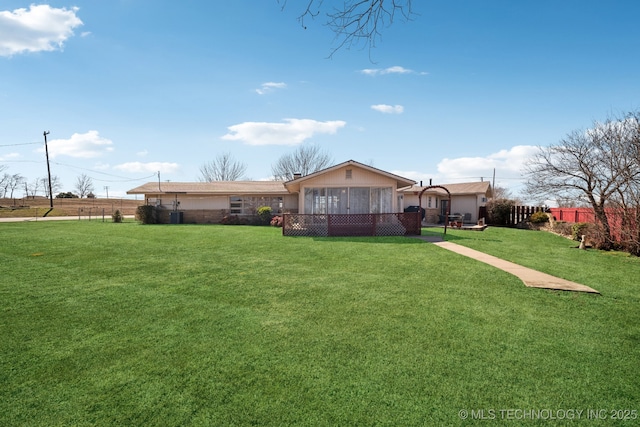 rear view of house with a lawn and a sunroom