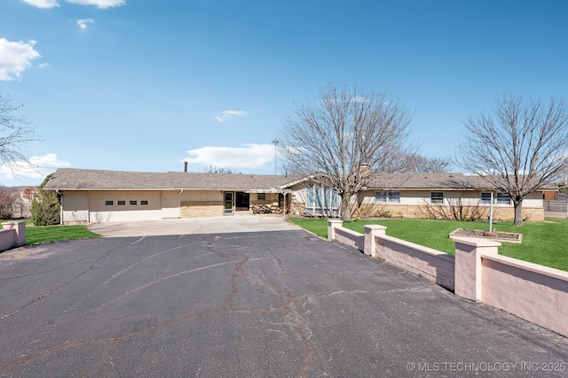 ranch-style home featuring a garage and a front lawn