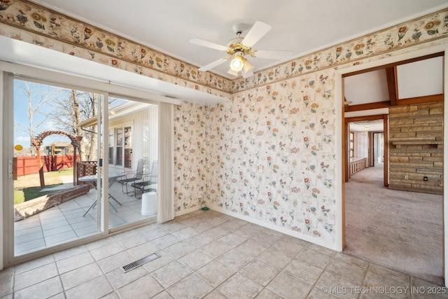 spare room with visible vents, wallpapered walls, baseboards, light colored carpet, and a ceiling fan