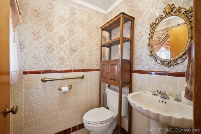 bathroom with a wainscoted wall, toilet, and wallpapered walls