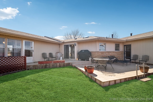 rear view of property with a yard, stone siding, and a patio area
