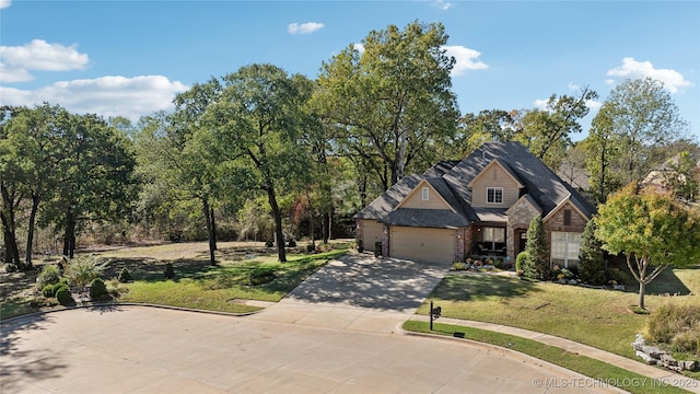 french country inspired facade with a front lawn, brick siding, a garage, and driveway