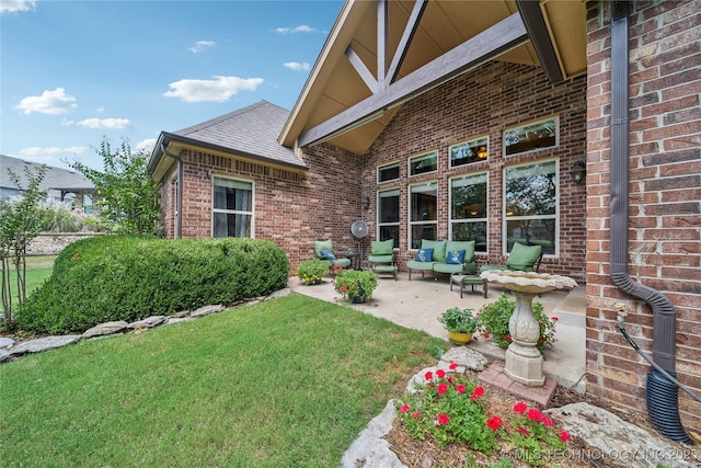 exterior space featuring a lawn, fence, roof with shingles, brick siding, and a patio area