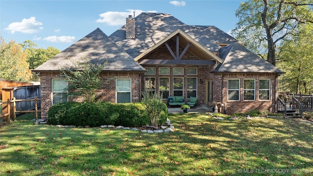 view of front of home with brick siding, a chimney, a front lawn, and fence