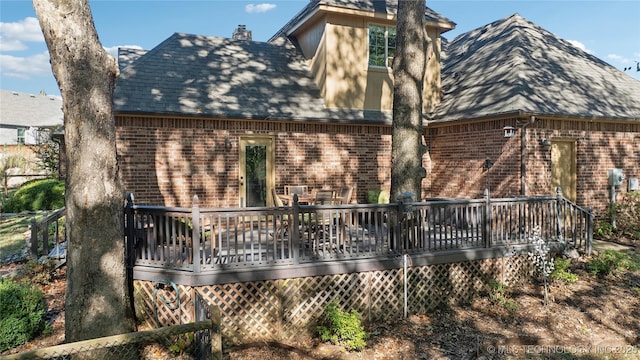 rear view of property with a wooden deck, brick siding, and a chimney