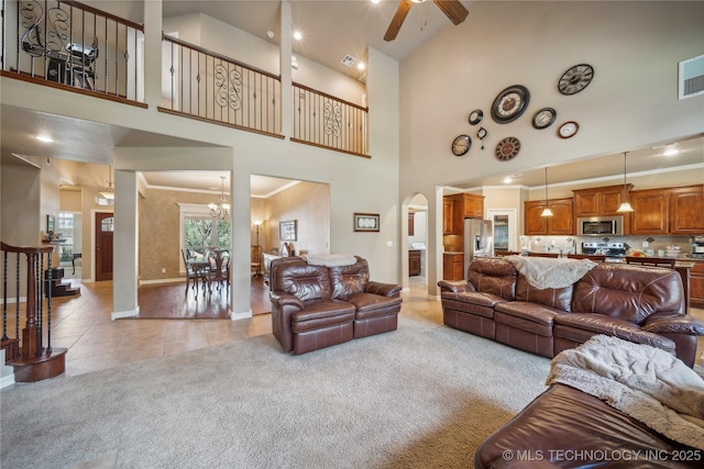 living area with stairway, light colored carpet, arched walkways, a high ceiling, and light tile patterned flooring