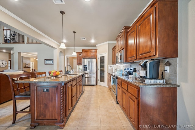 kitchen featuring a breakfast bar, a sink, stainless steel appliances, dark stone counters, and light tile patterned floors