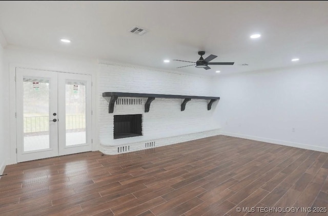 unfurnished living room with wood finished floors, visible vents, recessed lighting, french doors, and a brick fireplace