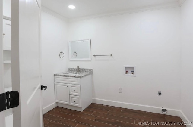 laundry room with wood finish floors, washer hookup, ornamental molding, a sink, and laundry area