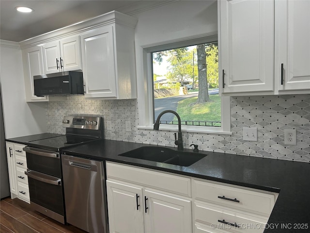 kitchen featuring a sink, stainless steel appliances, dark countertops, and white cabinets