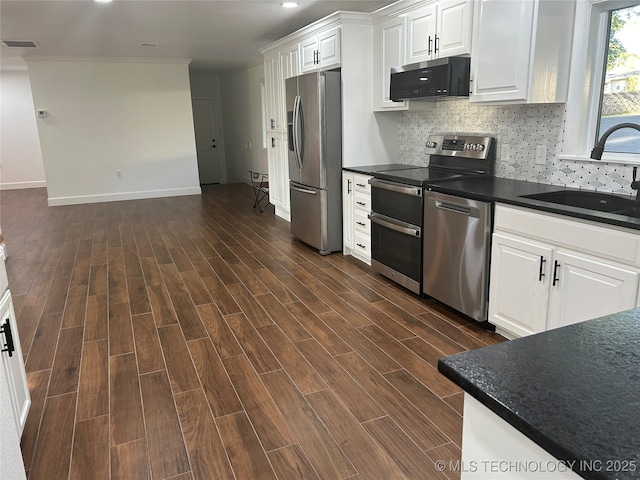 kitchen with visible vents, a sink, dark countertops, stainless steel appliances, and wood tiled floor