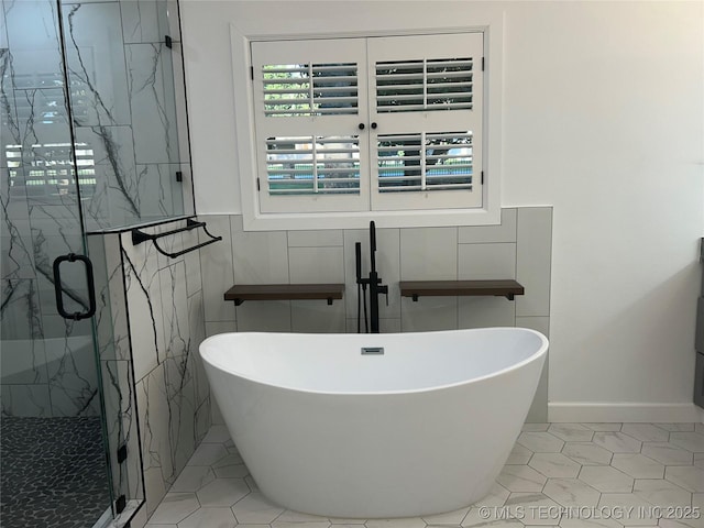 full bathroom with a freestanding tub, a marble finish shower, and tile walls