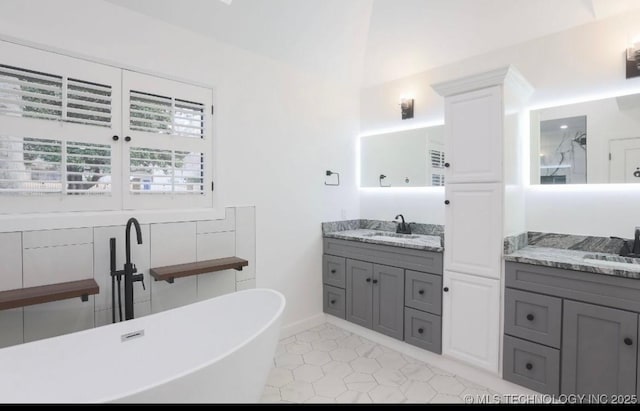 bathroom with a sink, a soaking tub, two vanities, and ornate columns