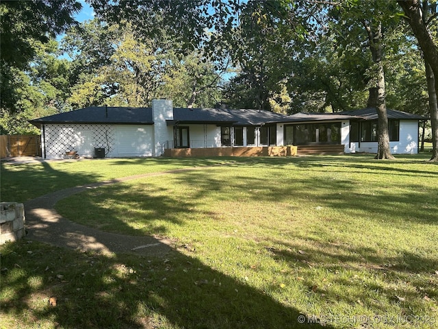 rear view of property featuring a lawn and a chimney