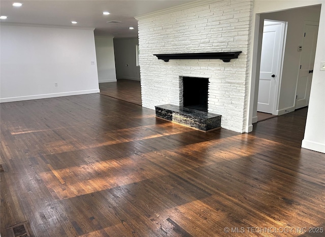 unfurnished living room with visible vents, crown molding, baseboards, a fireplace, and wood finished floors