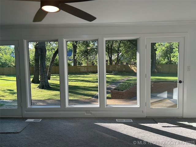 entryway with visible vents, plenty of natural light, ceiling fan, and carpet flooring