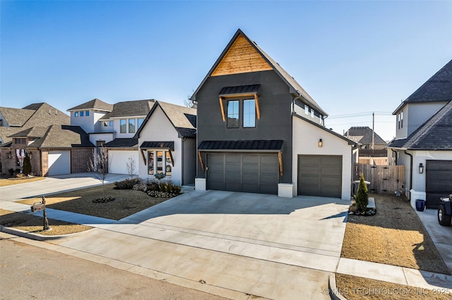 view of front of property featuring fence, concrete driveway, metal roof, an attached garage, and a standing seam roof