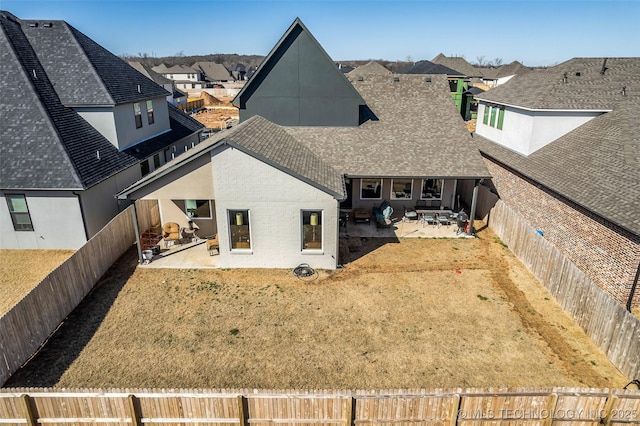 rear view of house with a patio area, a residential view, a fenced backyard, and a shingled roof