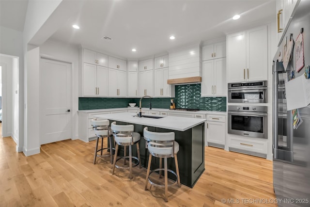 kitchen with a kitchen breakfast bar, light wood-type flooring, stainless steel appliances, and a sink