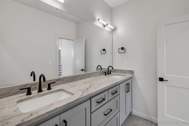 full bath featuring a sink, baseboards, double vanity, and tile patterned flooring