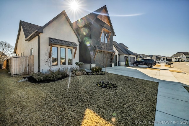 view of front of property with an attached garage, fence, a residential view, and driveway