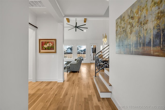 hallway with light wood finished floors, visible vents, stairs, and baseboards