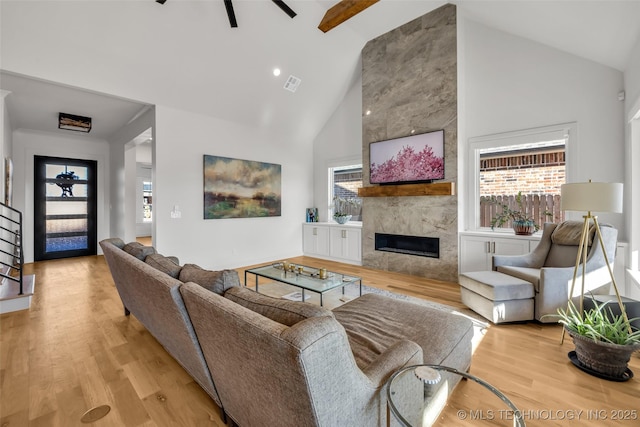 living area featuring light wood-type flooring, visible vents, high vaulted ceiling, plenty of natural light, and a fireplace