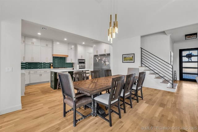 dining area featuring stairway, baseboards, light wood-style floors, and visible vents