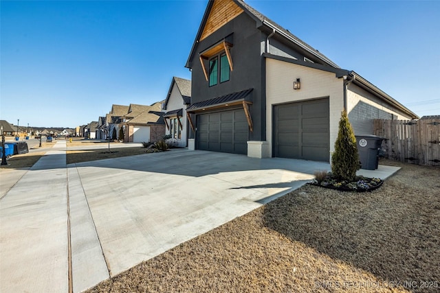 view of property exterior with fence, a residential view, concrete driveway, a garage, and brick siding