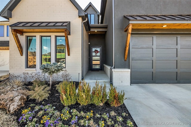 doorway to property with brick siding, an attached garage, metal roof, and a standing seam roof