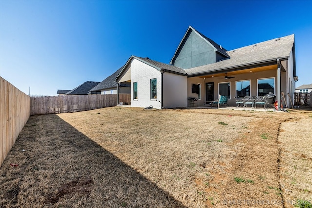 rear view of house featuring a fenced backyard, stucco siding, ceiling fan, a patio area, and a lawn