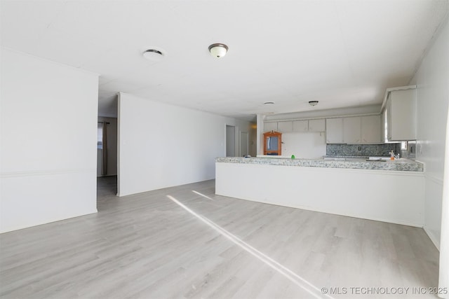 kitchen featuring gray cabinetry, tasteful backsplash, light wood-style floors, a peninsula, and light countertops